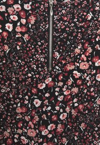 Stoff mit Blumenmuster in Schwarz mit roten, rosa und weißen Blumen. Zentrale Reißverschlussöffnung mit metallischen Beschlägen. Strukturiert Oberfläche.