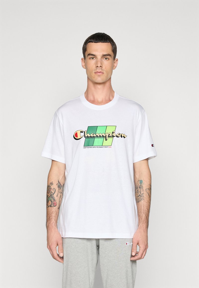 Camiseta de algodón blanca con un logotipo "Champion" multicolor sobre un fondo degradado verde; corte relajado y mangas cortas.