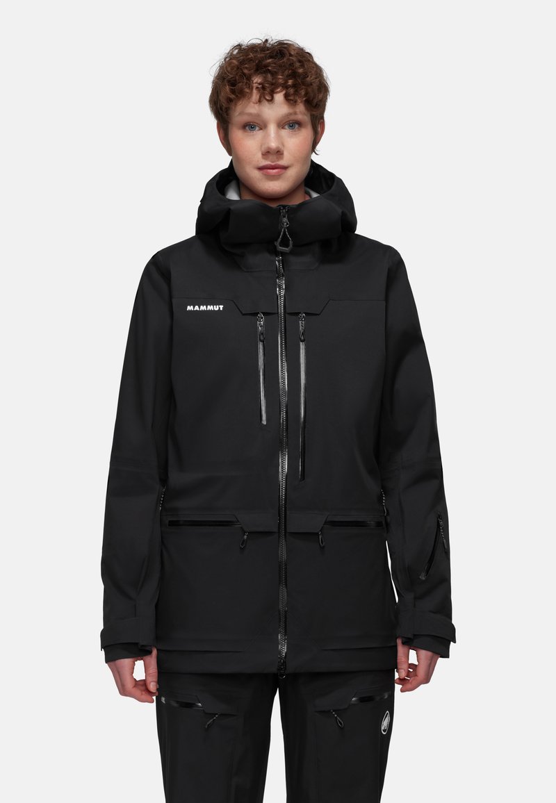 Svart vattentålig jacka med hög krage, flera dragkedjefickor och justerbara ärmslut. Har en stilren, minimalistisk design.