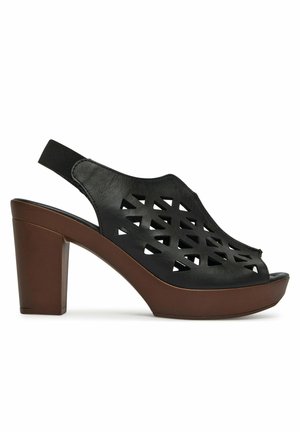 Schwarze Slingback-Sandale aus Leder mit geometrischen Ausschnitten, brauner Plateau-Sohle und Blockabsatz.