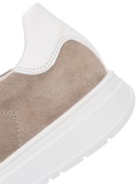 Close-up of sneaker heel showing beige suede upper, white leather collar, and thick white rubber sole with textured tread.