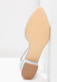 Chaussure en daim bleu clair avec un embout pointu, présentant une tige lisse et une semelle texturée marron clair. Taille indiquée comme 37.