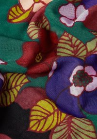 Tessuto floreale multicolore con grandi fiori viola e rossi, foglie verdi e una superficie tessuta e textured.