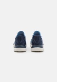 Sneakers blu navy con una tomaia texture, tallone liscio, dettagli azzurri e suola in gomma bianca, progettati per comfort e supporto.