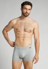 Boxers en coton gris avec une ceinture douce et une poche à l'avant. Le tissu a une texture lisse et un minimum de détails de couture.