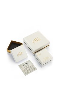 Tre vita lådor med gyllene detaljer och logotyp, varierande i storlek, bredvid ett texturerat certifikat som beskriver produktens äkthet.