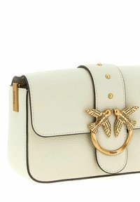 Borsa in pelle color crema con chiusura in tonalità oro con due uccelli che si fronteggiano e una targhetta con il logo Pinko sul lato.