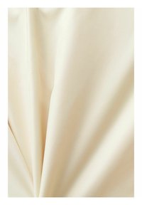 Tissu de couleur crème avec une texture lisse et des plis doux créant des ombres et des reflets délicats.