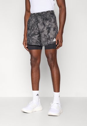 Pantalones cortos deportivos con patrón en negro y gris, con forro interior negro incorporado. Cuenta con una cintura elástica con marca y acento de logo blanco.