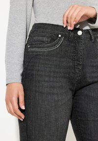 Jeans in denim nero con una leggera elasticità, caratterizzati da una tasca frontale decorata con cuciture decorative e piccoli strass, con un design a vita alta.