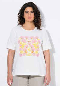 T-shirt à manches courtes blanche avec un graphique floral coloré en rose et jaune, comportant le texte "Fiesta de las Flores" au centre.