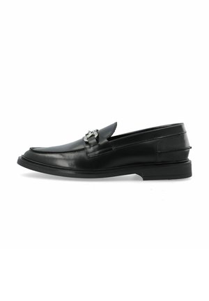 Mocasines de cuero negro con punta redonda, una hebilla decorativa de plata en el empeine y un tacón bajo de goma para mayor agarre.
