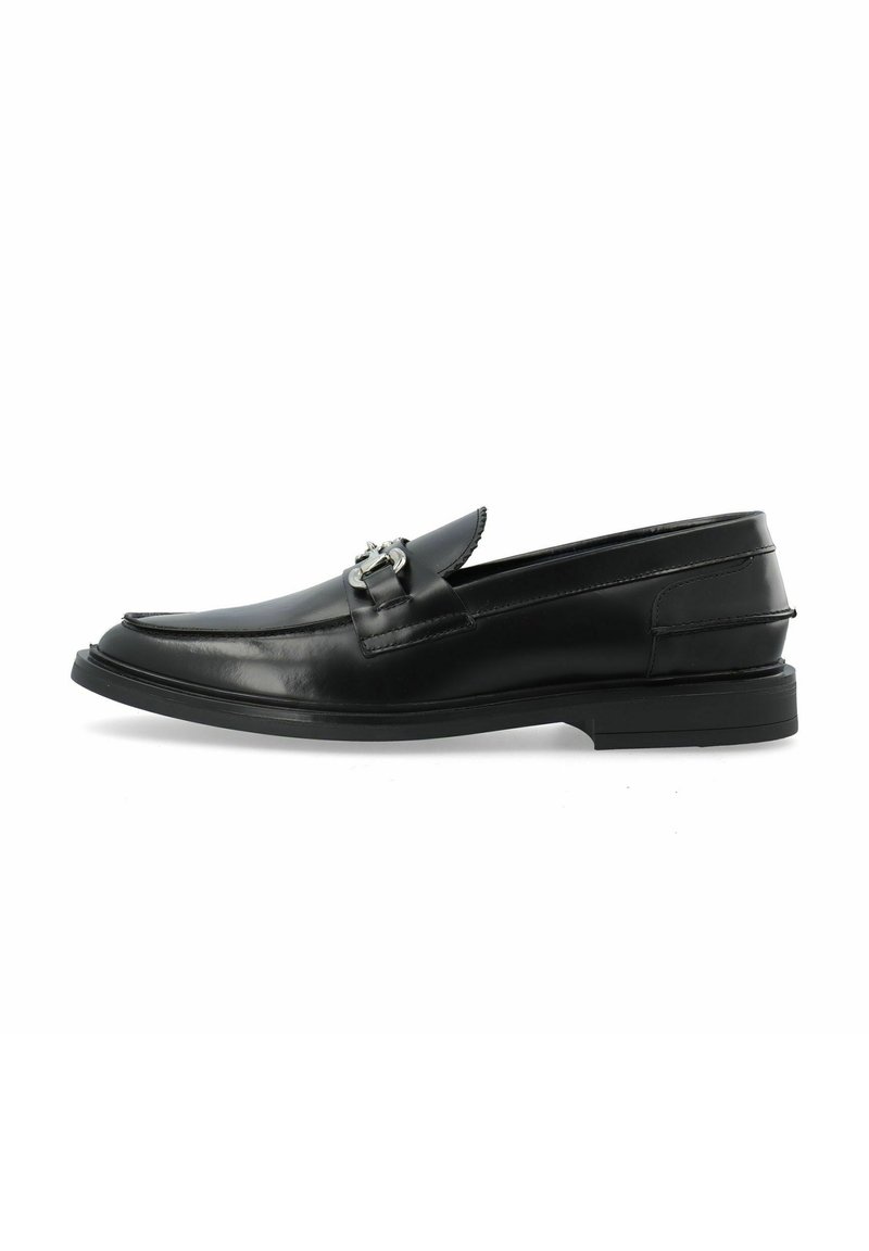 Mocasines de cuero negro con punta redonda, una hebilla decorativa de plata en el empeine y un tacón bajo de goma para mayor agarre.