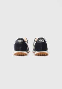 Sapatilhas de corrida em camurça azul-marinho com detalhes brancos, apresentando uma sola texturizada e um tab que, em preto, exibe "NIKE" em branco.