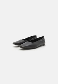 Bailarinas de cuero negro con un diseño de punta. Textura lisa, estilo minimalista, con una etiqueta de marca en el lateral y una suela de perfil bajo.