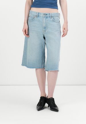 Lyseblå denim culotter med en rå kant, løs pasform, to forlommer og høj talje. Sammen med sorte snørebånds ankelstøvler.