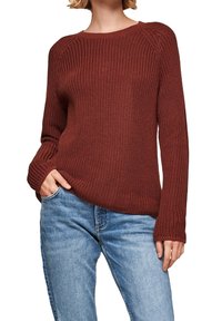 Gebreide trui in roestkleur met een ronde hals, geribbelde zoom en lange mouwen. Draagt over lichtblauwe spijkerbroek, met een getextureerd ontwerp.