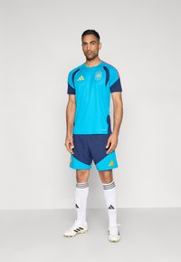Blå och marinblå fotbollskit med texturerad tröja, med tre gula ränder. Inkluderar matchande shorts och vita strumpor med svarta detaljer.