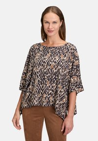 Wydrukowana ponczo z luźnym krojem, dekoltem w łódkę, rękawami 3/4 oraz brązowym, granatowym i kremowym geometrycznym wzorem.