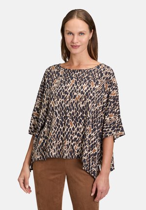 Tunique poncho imprimée présentant une coupe ample, un col bateau, des manches trois-quarts et un motif géométrique marron, marine et crème.