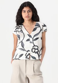 Blusa bianca a maniche corte e scollatura a V con stampa floreale nera. Realizzata in tessuto morbido, presenta piccoli bottoni e una vestibilità comoda.