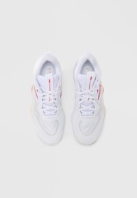 Ζευγάρι λευκών αθλητικών παπουτσιών με κόκκινες λεπτομέρειες, διχτυωτό επάνω μέρος, δεμένα κορδόνια και το κείμενο «Momentum Elite» ορατό στις γλώσσες, θέα από πάνω.