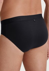 Zwarte katoenen onderbroeken met een gladde textuur, voorzien van een brede zwarte tailleband met de opdruk "CALIDA." Eenvoudig ontwerp, geen patronen of accenten.