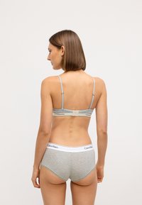 Sivý bavlnený bralet s nastaviteľnými ramienkami a zapínaním na chrbte, v kombinácii so zodpovedajúcimi sivými nohavičkami so bielym pásom a logom.