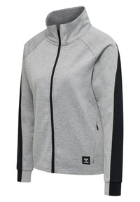 Szara kurtka zapinana na zamek z czarnymi panelami po bokach, wysokim kołnierzem i elastycznymi mankietami. Charakteryzuje się subtelną fakturą i małym logo na końcu.