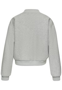 Pelēks īss svārku krekls ar ribotu apkakli un aprocēm, ar mīkstu tekstūru un nolaistiem plecu šuvēm, kas nodrošina brīvu piegriezumu.