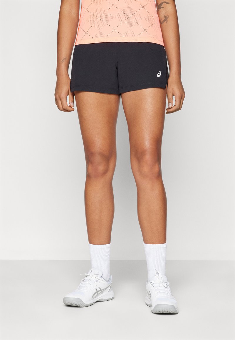 Black athletic shorts with a smooth texture, worn with a pink patterned tank top, white crew socks, and white sneakers.