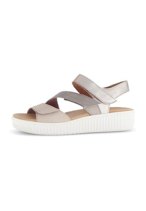 Light beige sandals with cross-strap design, soft leather material, cushioned footbed, and rubber sole with textured grip.