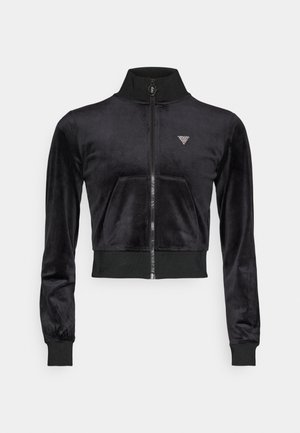 Jachetă neagră, scurtă, cu fermoar, realizată dintr-un material moale și neted, cu mansete elastice, având o singură pungă în față și un logo în formă de diamant pe piept.