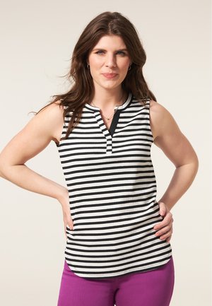 Zwart-witte gestreepte mouwloze top met een henley-halslijn en textuurstof, gecombineerd met paarse broek, op een lichte achtergrond.