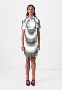 Juoda ir balta dryžuota polo suknelė su trumpomis rankovėmis, apykakle ir raišteliu juosmens zonoje. Sukurta prigludusiu siluetu.