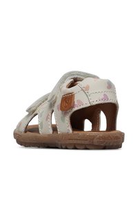 Sandali per bambini con una tomaia bianca che presenta un motivo a cuore nei colori pastello, cinturini regolabili e una suola in gomma marrone.
