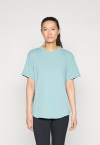 Lys blå, kortermet t-skjorte i en avslappet passform med rund hals og glatt tekstur, parret med svarte leggings.