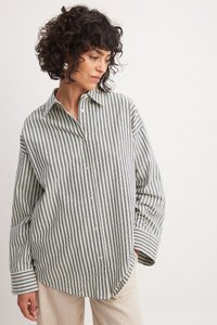 Striped button-up shirt in green and white. Soft fabric, relaxed fit, long sleeves with folded cuffs, and a pointed collar.