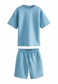 Vaaleansininen puuvillainen lyhythihainen t-paita, jossa pyöreä pääntie, yhdistettynä vastaaviin vaaleansinisiin shortseihin, joissa on joustava vyötärönauha ja taskut.