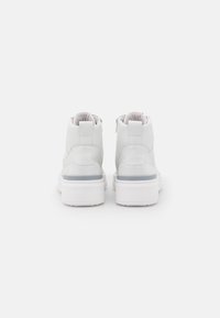 White leather high-top sneakers with a raised heel and smooth texture, featuring a contrasting grey panel at the rear and zippers on the sides.
