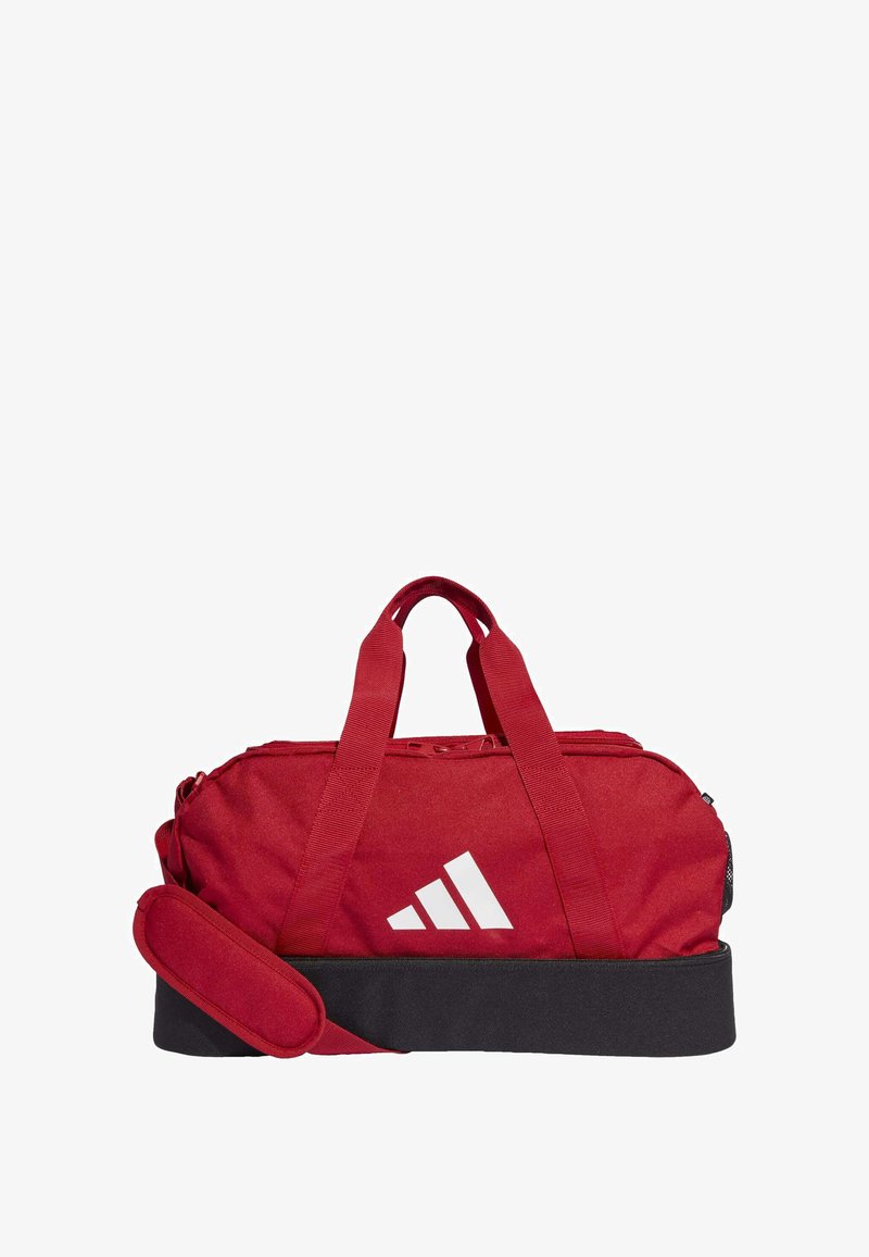 Rode sporttas met dubbele handgrepen, ritsclosures, zwarte basis en wit logo; gemaakt van duurzaam materiaal met een gladde textuur en strakke lijnen.