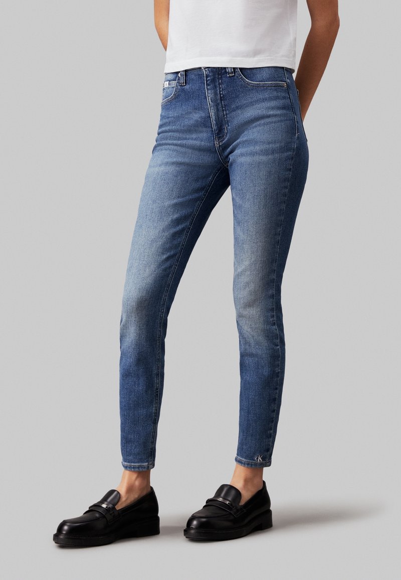 Smala blå denimjeans med en urtvättad finish, femfickorsdesign och synliga sömdetaljer. Matchas med svarta loafers.