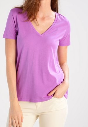 Lila V-Ausschnitt T-Shirt aus weichem Baumwollstoff, mit kurzen Ärmeln und lockerer Passform, kombiniert mit hellen Hosen.