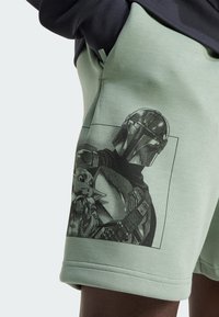 Light green cotton shorts featuring a graphic print of a character in armor holding another character, with a smooth texture and relaxed fit.