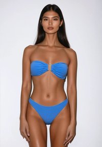 Blauwe bandeau-bikini met geplooide stof en gouden hardware detail in het midden, gecombineerd met high-waisted onderstukken. Zachte textuur.