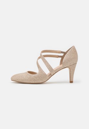 Pompe en tissu pailleté beige avec un bout pointu, deux brides croisées et un talon de 7 cm. Texture lisse avec un éclat subtil, adaptée aux vêtements de cérémonie.