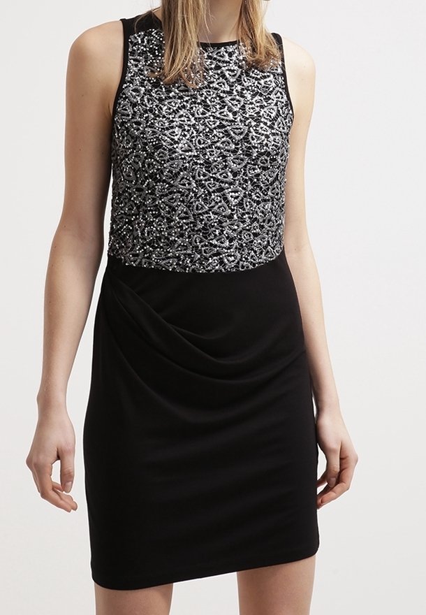Robe noire sans manches avec une jupe ajustée et un haut orné de sequins argentés avec des motifs géométriques complexes.
