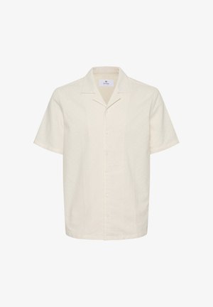 Rövid ujjú ing világos bézs színű szövetből, gallérral, gombos záródással és laza szabással, finom textúrával és minimális részletezéssel.