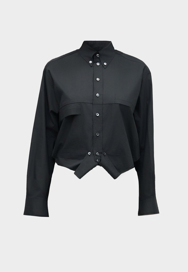 Chemise noire à manches longues avec des boutons, ourlet court et pointu et col boutonné, sur un fond uni.