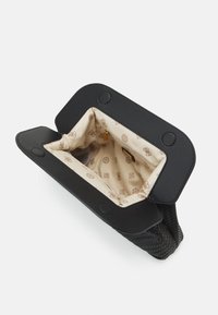 Czarna pleciona torba z gładką skórzaną klapką. Wnętrze wyściełane kremowym materiałem z subtelnym wzorem logo i złotymi akcentami.